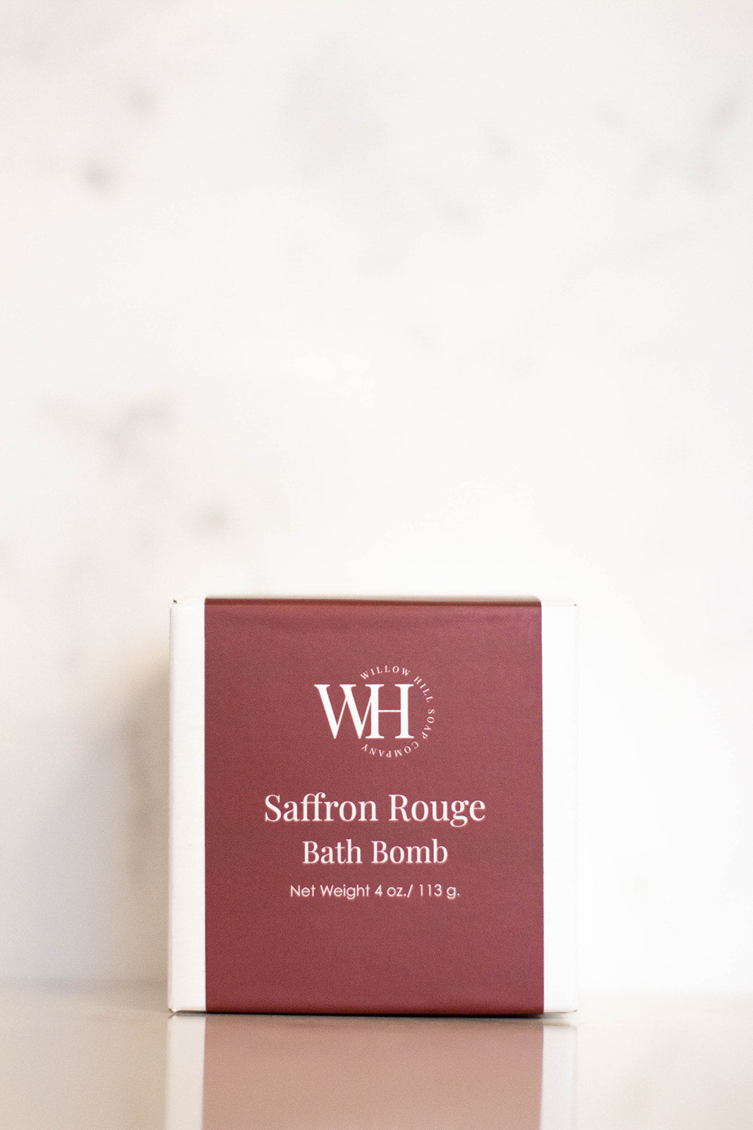 Red and white box with Saffron Rouge Bath Bomb on the packaging. 